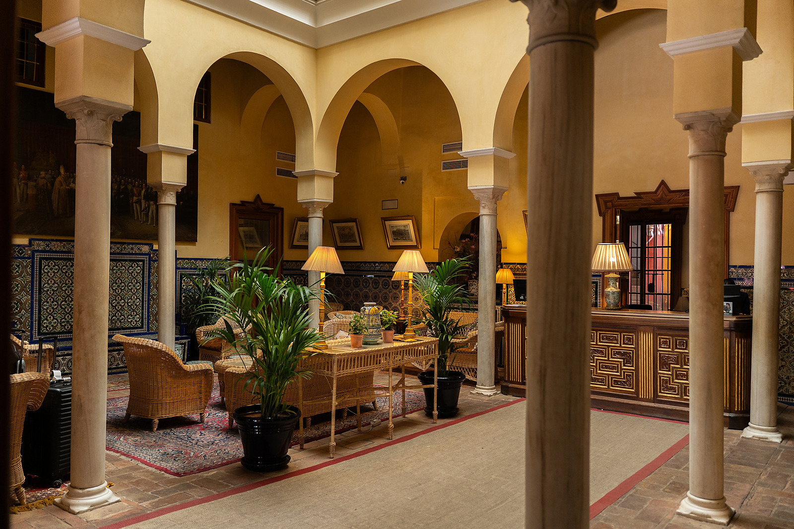 A columned courtyard with tiled walls and lantern light